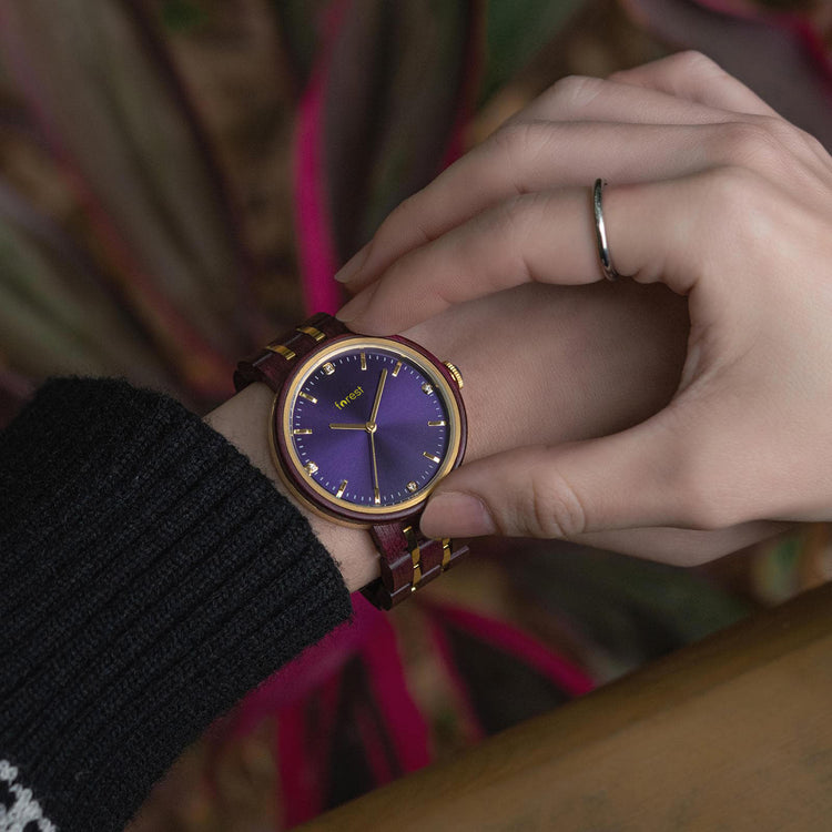 a woman adjusting the time on her red and gold wooden watchwood watch