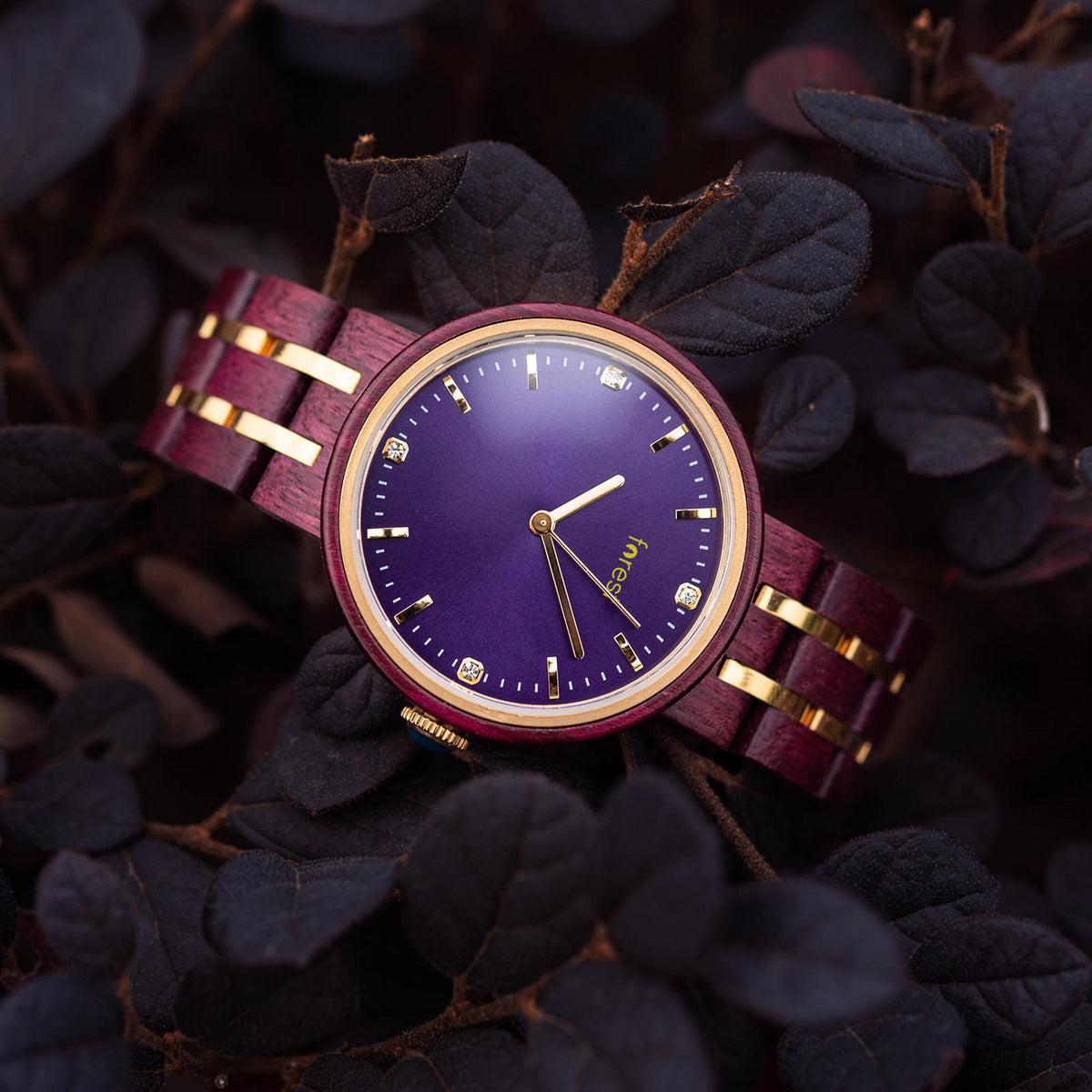 Red and gold womans wood watch hanging from an angle on a branch