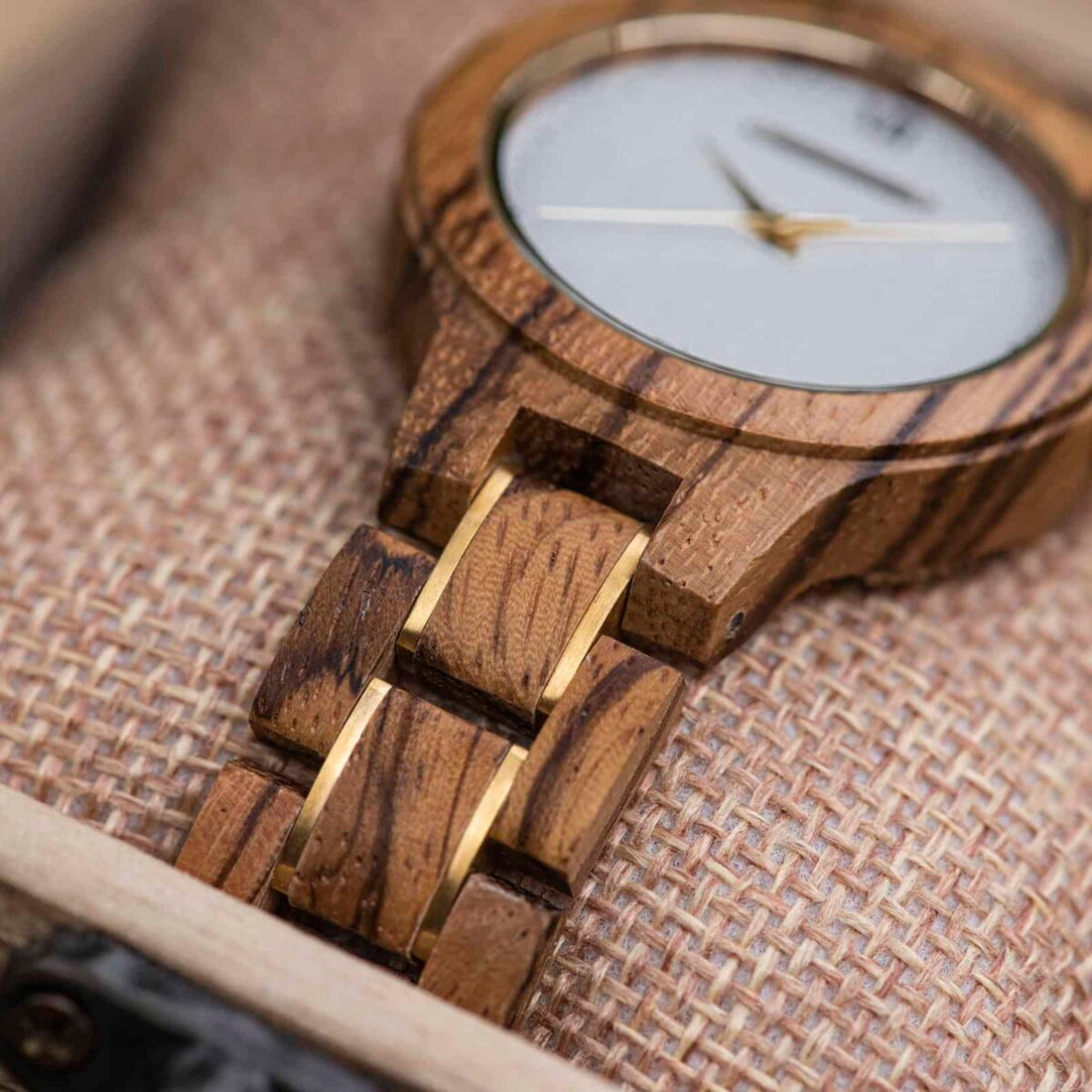 Close view of the Zara watch bracelet, zebrawood links with dark stripes and gold accents