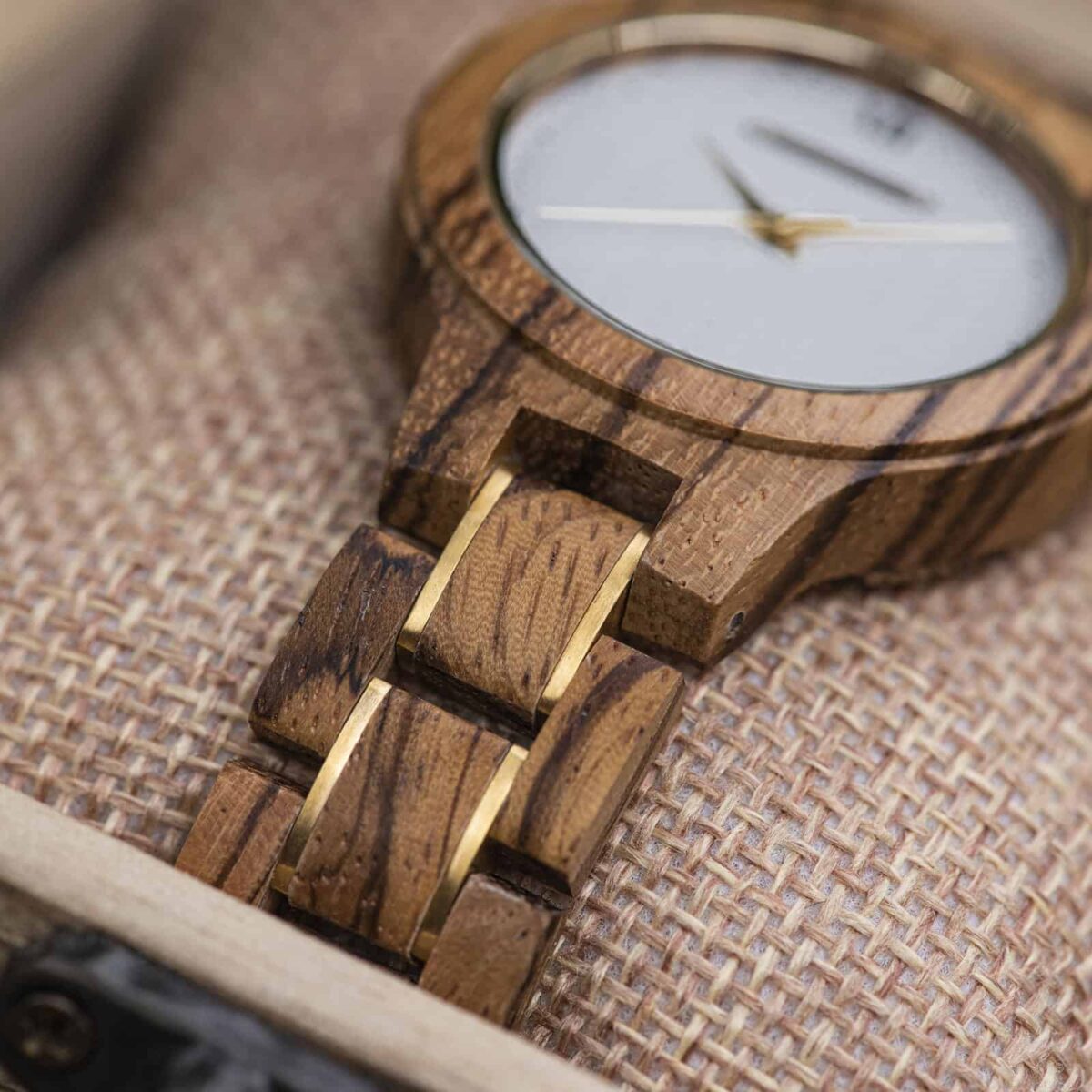 Close view of the Zara watch bracelet, zebrawood links with dark stripes and gold accents