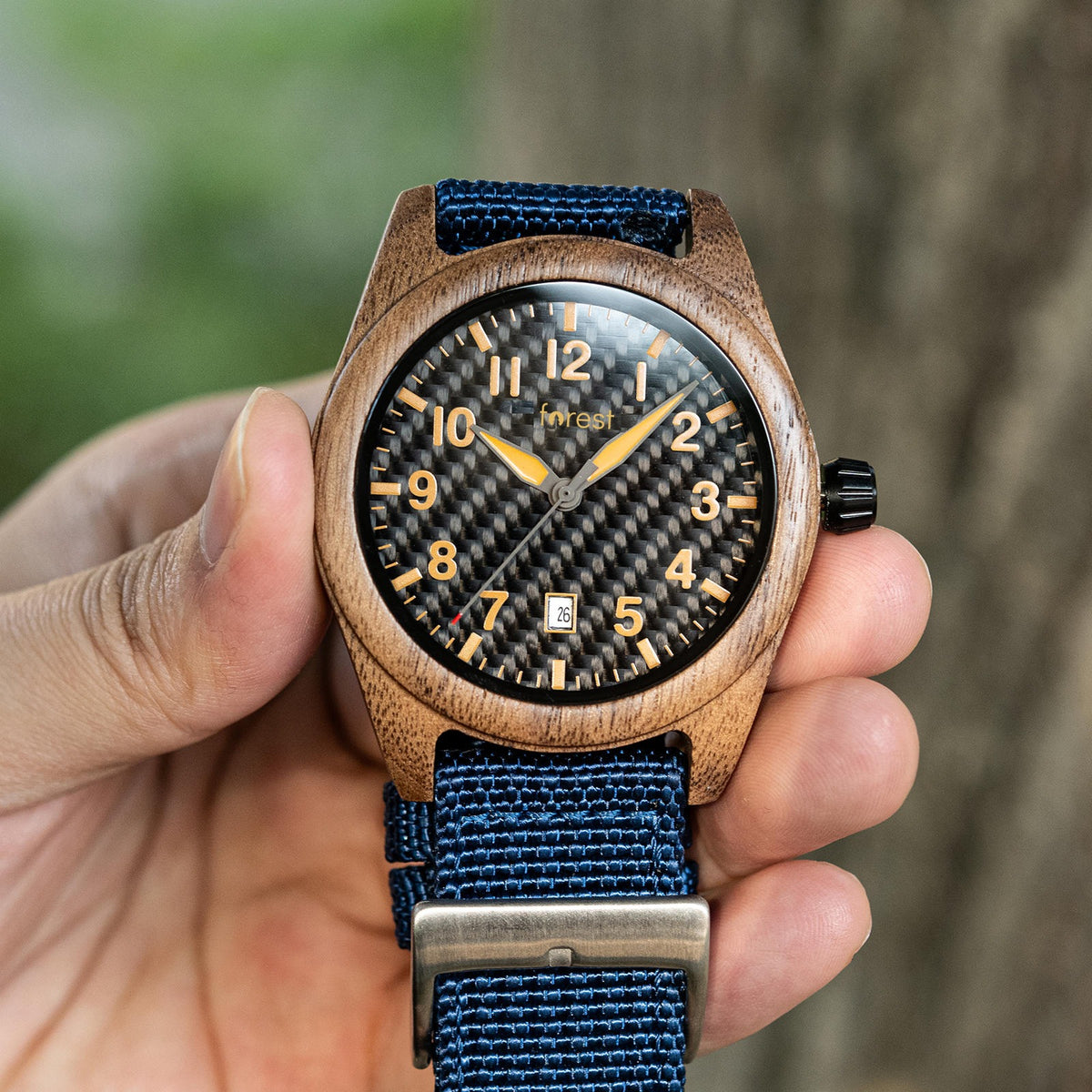 Scout wooden watch held in a hand in front of a tree