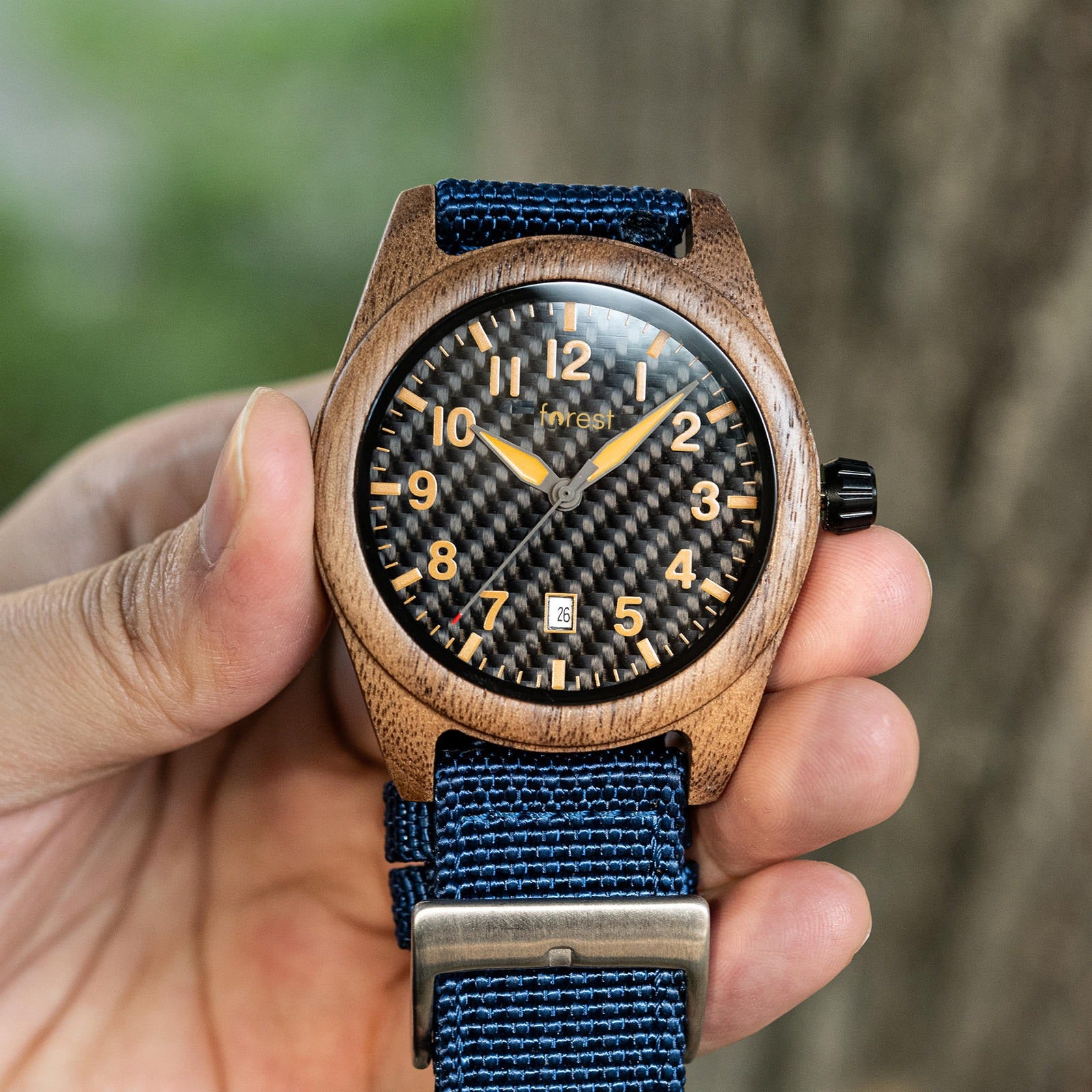 Scout wooden watch held in a hand in front of a tree