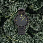 Umber black wooden watch on patterned green leaves