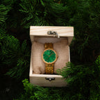Emerald face wood watch with olivewood strap in a gift box suspended in a tree