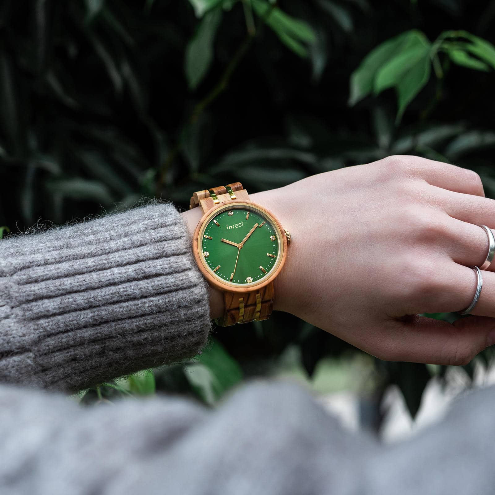 A womans wrist with the IVY wood watch with emerald green face