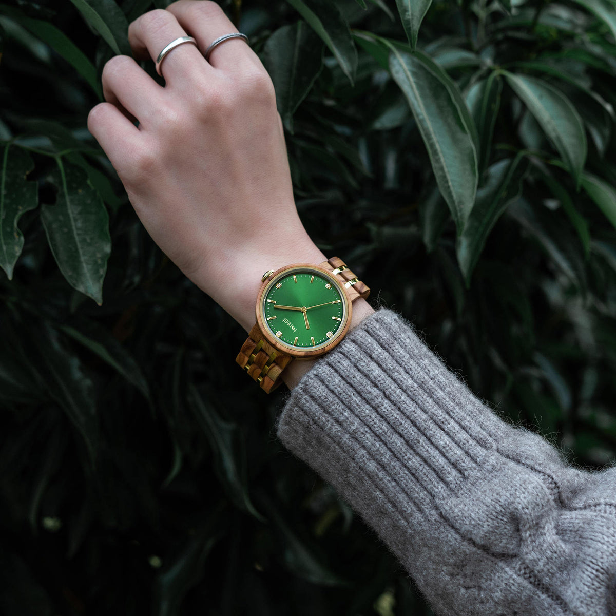 IVY Forest watch with the emerald face on a womans wrist as she touches the tree