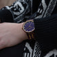 A womans red wood watch slightly covered by a jumper