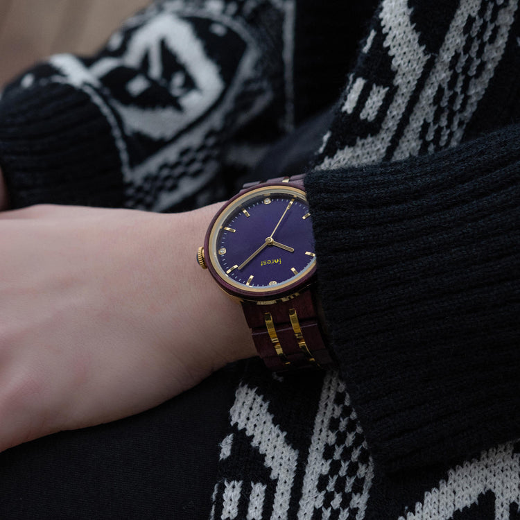 A womans red wood watch slightly covered by a jumper