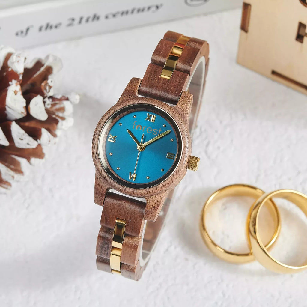 Blue dial Midnight wooden watch beside two gold rings on a white surface