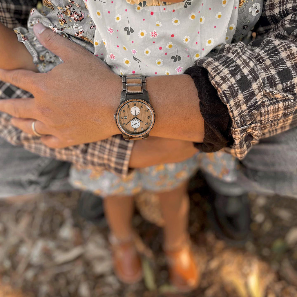 Man holding child while wearing Barrel whiskey wood watch