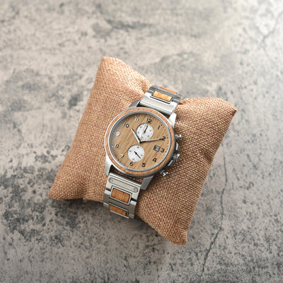 Barrel men's wood watch from whiskey barrels resting on a pillow on a concrete top