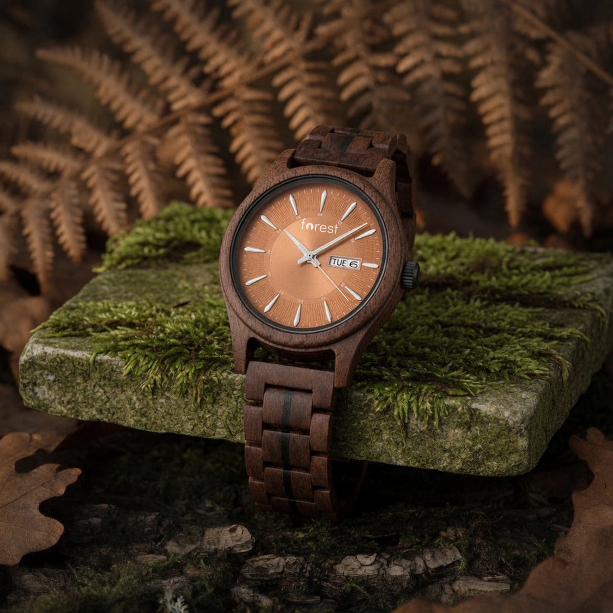 Bracken walnut watch with copper dial, draped over the edge of a mossy stone, bracelet hanging
