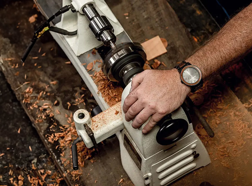 Craftsman handcrafting a wooden watch on a lathe