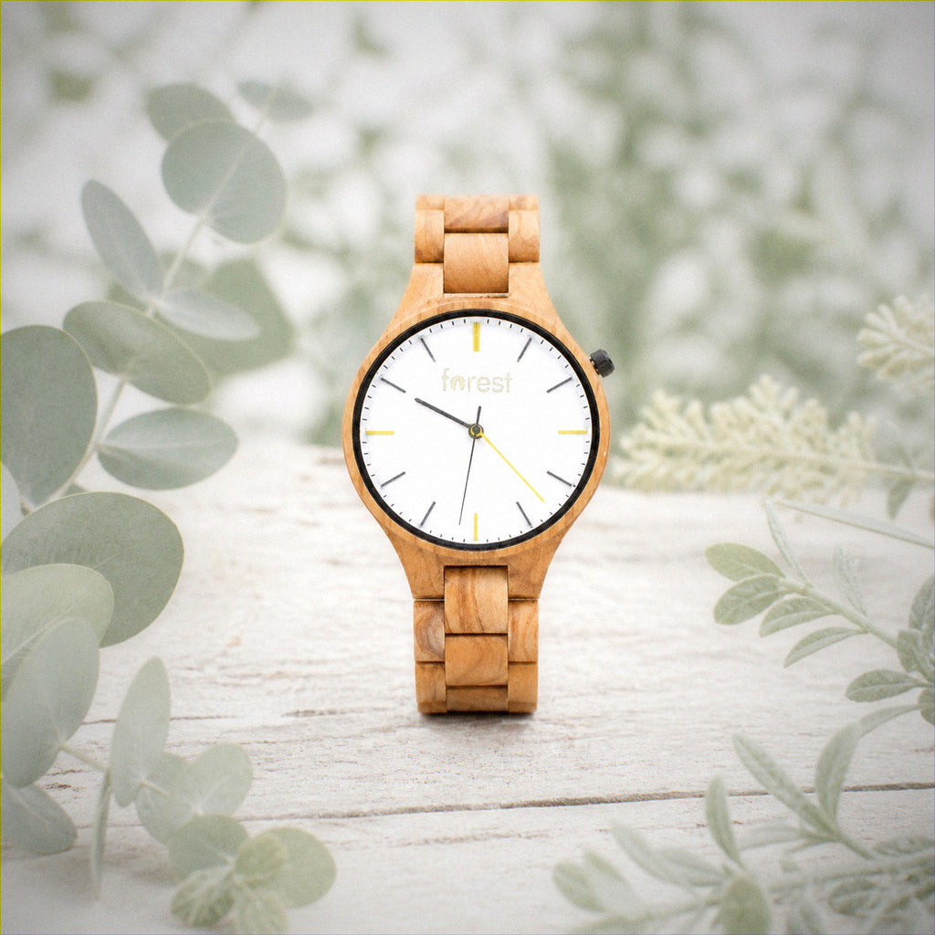 Dawn wooden watch among pale wood and eucalyptus leaves
