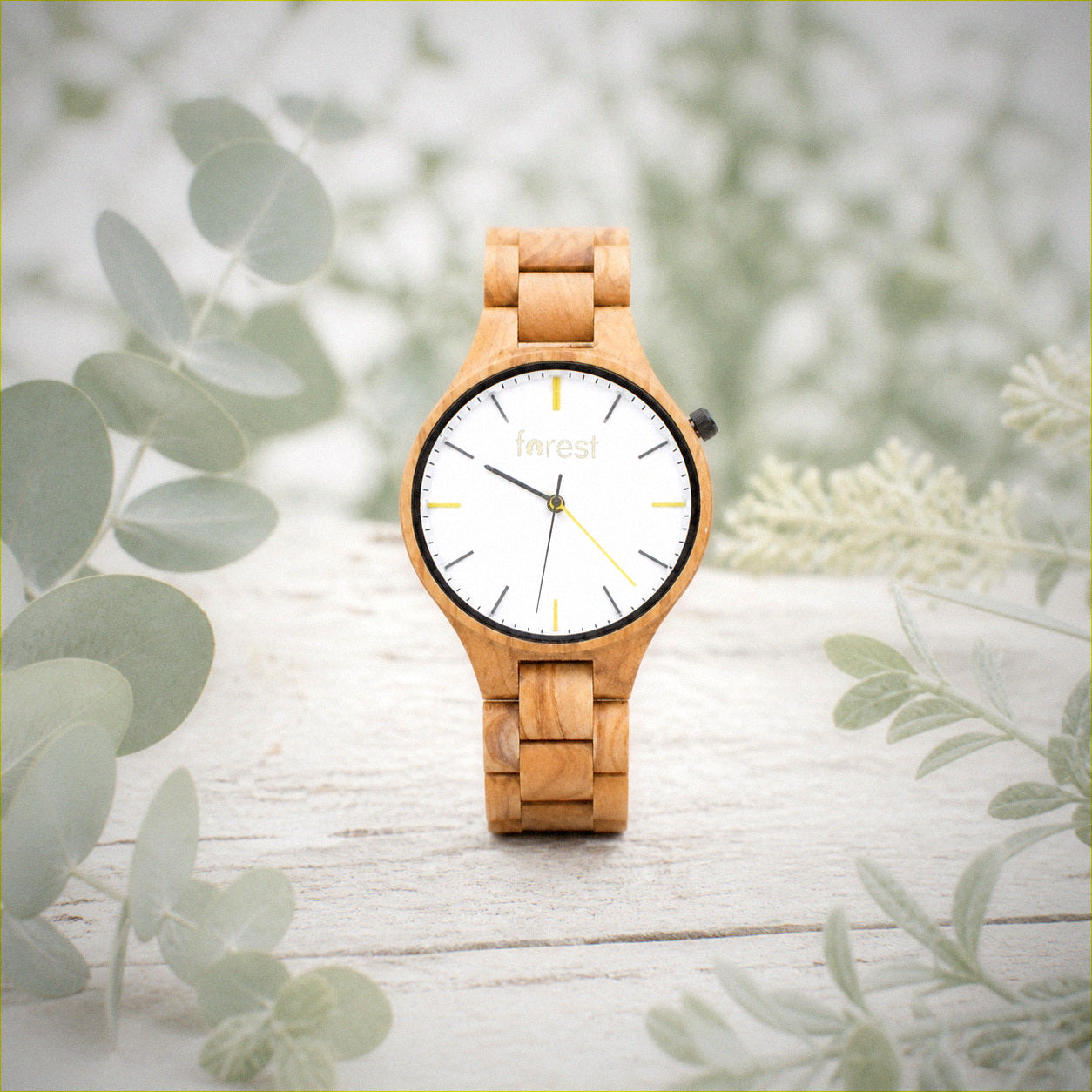 Dawn wooden watch among pale wood and eucalyptus leaves