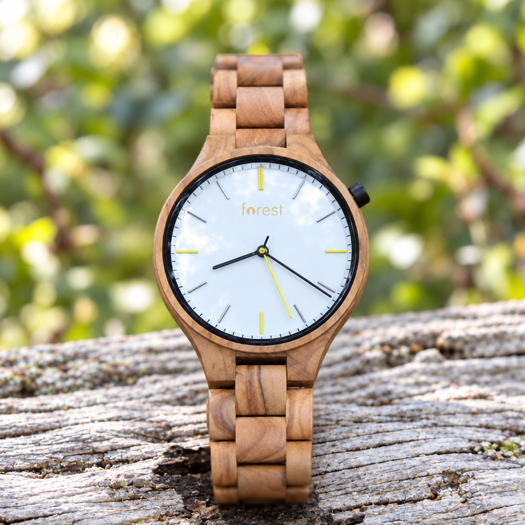 Dawn olivewood watch with a white dial, standing on pale driftwood