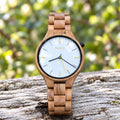 Dawn olivewood watch with a white dial, standing on pale driftwood