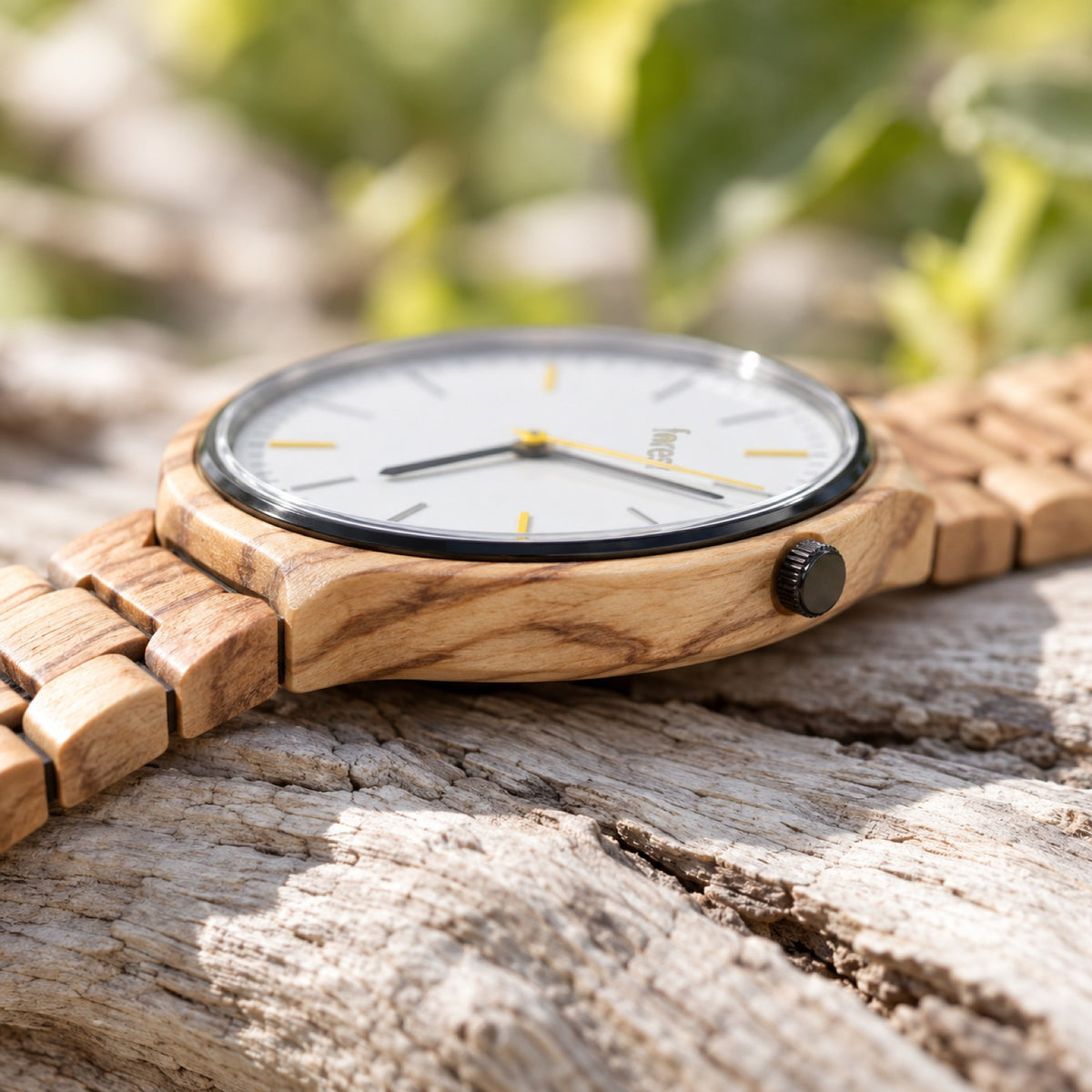 Side view of the Dawn olivewood watch on pale driftwood, showing its slim case and crown