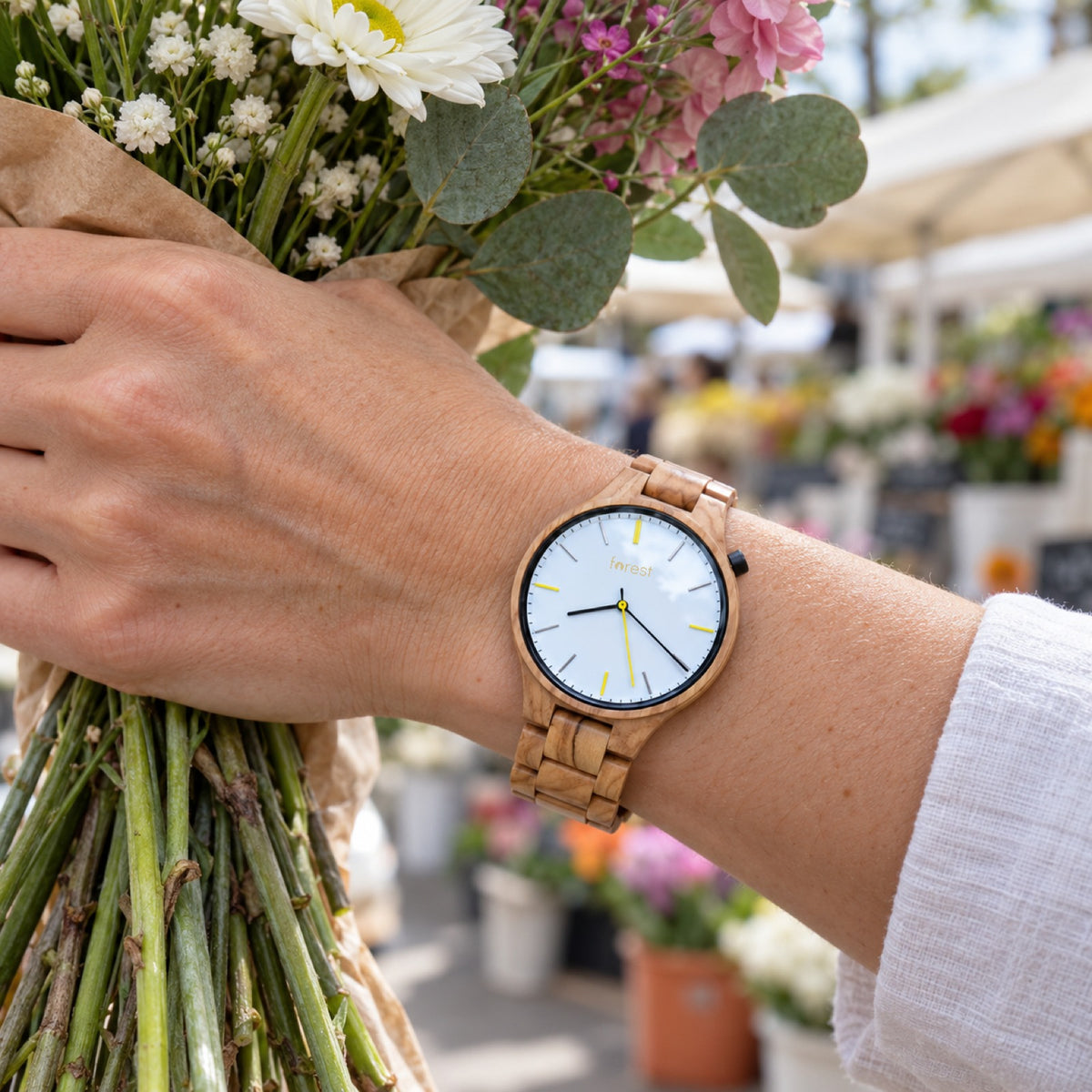Dawn olivewood watch on a woman's wrist, holding fresh flowers at a market