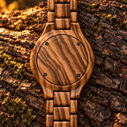 Dusk zebrawood watch lying face down on a log, showing its wooden back