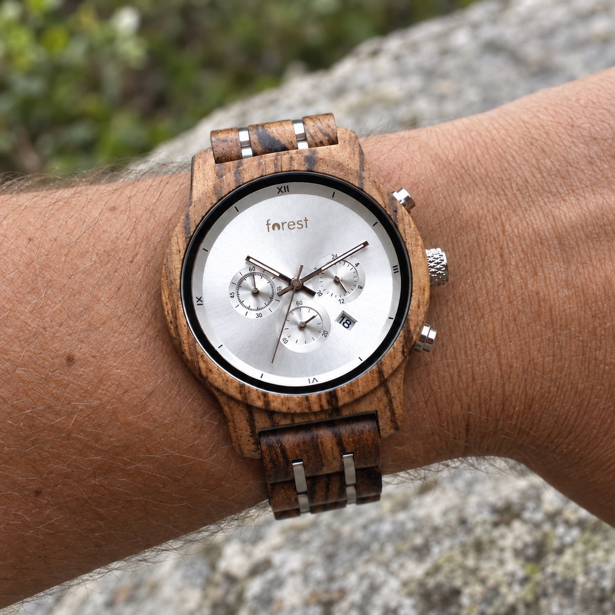 Ember wooden watch worn on a wrist outdoors, showing its silver chronograph dial