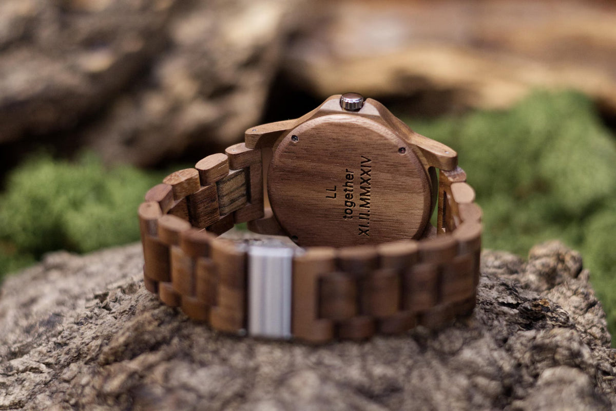 An engraved wooden caseback on a Forest Windsor watch, reading LL, together, and a date in Roman numerals across three short lines