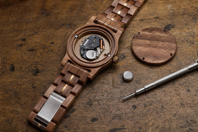 A Forest watch open on the bench with its caseback off, a fresh battery and a screwdriver