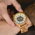 Gold/silver accent WOODHAVEN wooden watch held in the hand, showing the skeleton dial