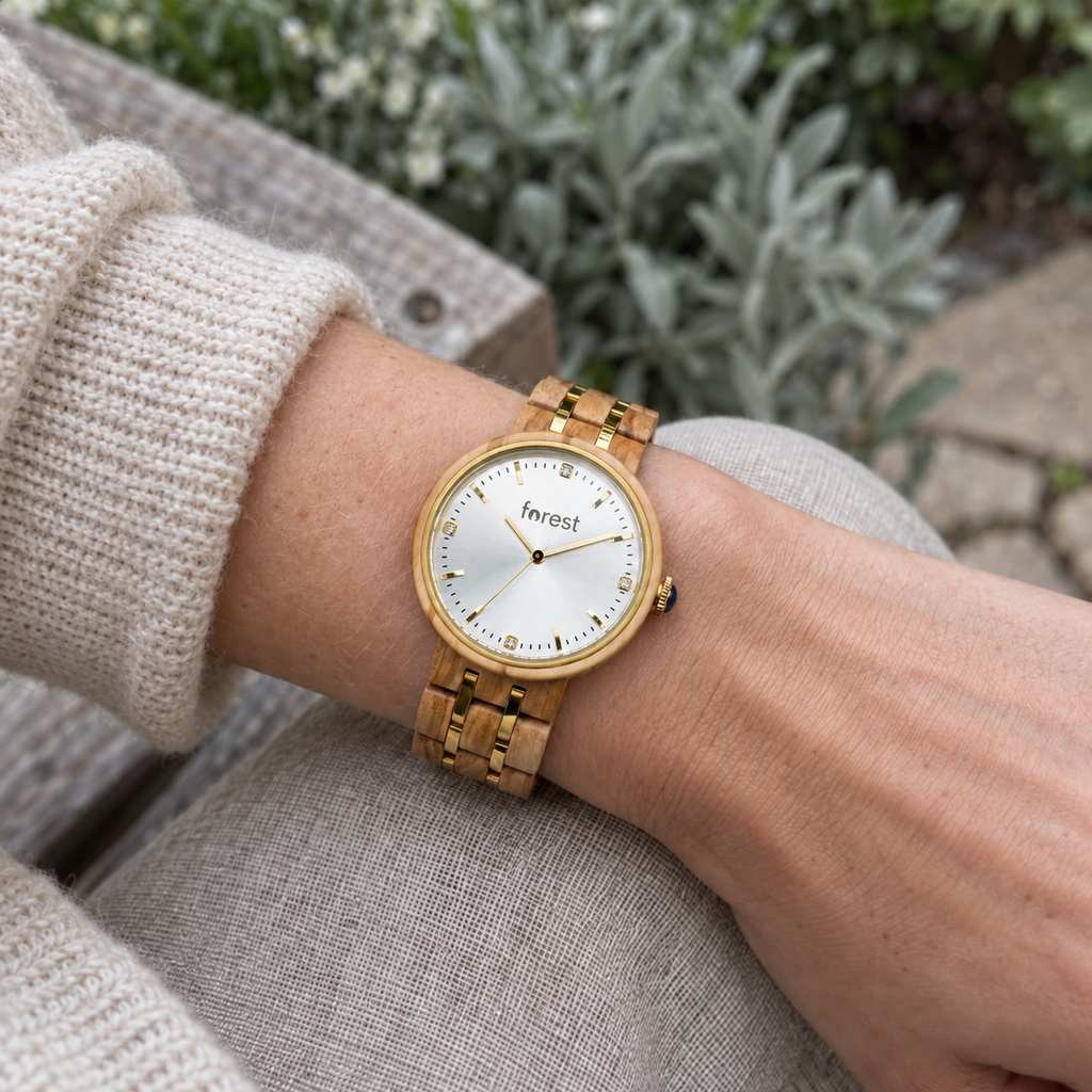 Victoria olivewood and gold watch worn with a cream knit sleeve on a garden bench