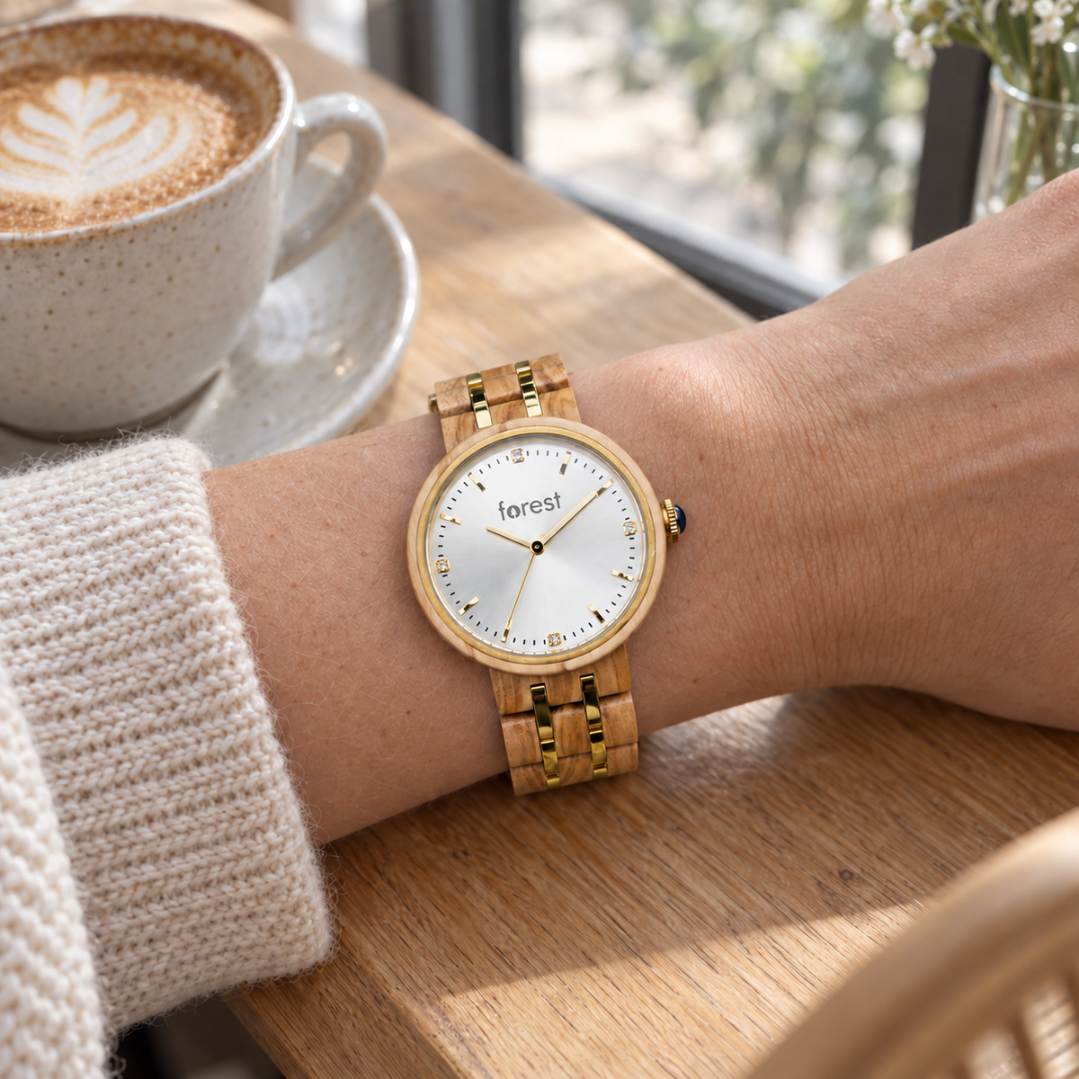 Victoria olivewood and gold watch on a wrist beside a coffee at a cafe window