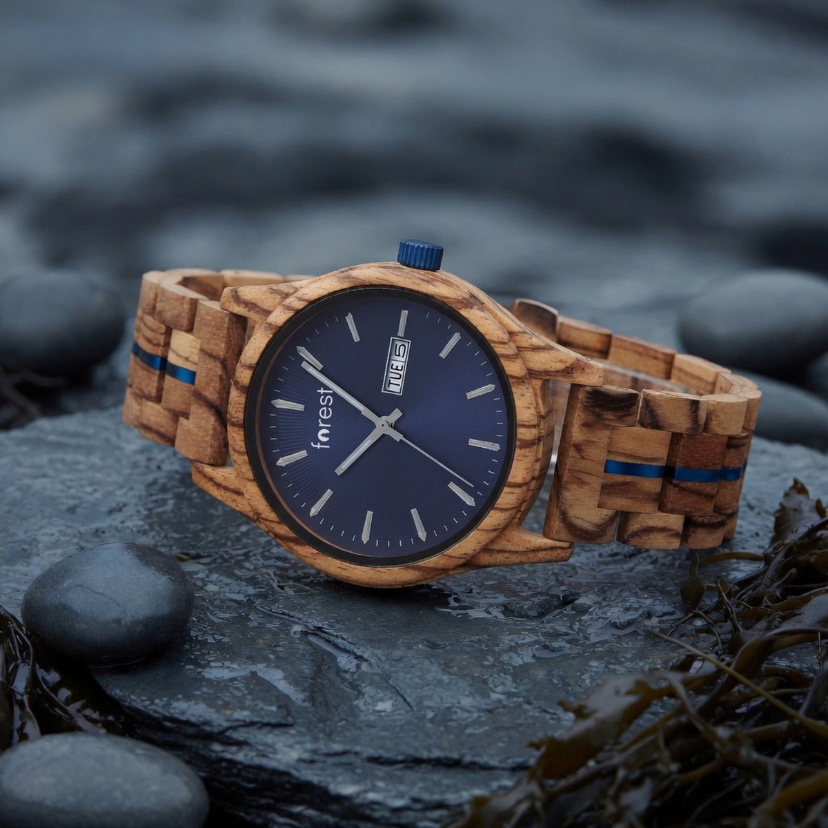 Harbour zebrawood watch with navy dial, lying on wet coastal slate at a three-quarter angle