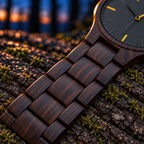 Close-up of Nightfall's slim ebony bracelet links on a log at blue hour