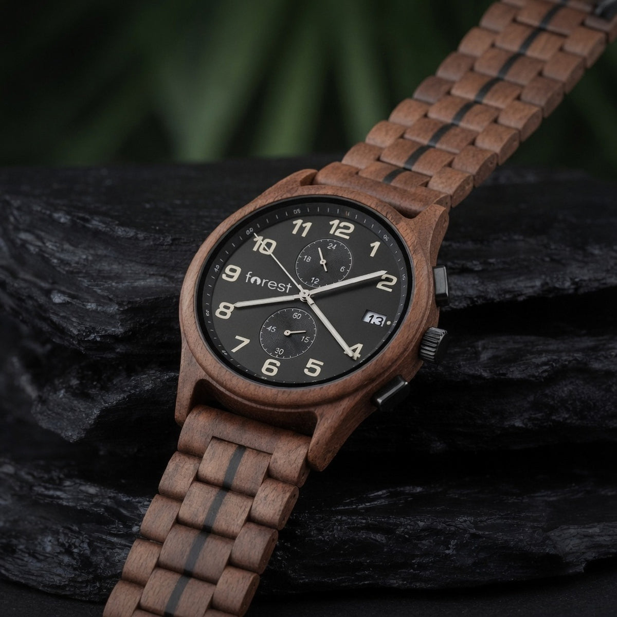 Raven walnut chronograph with black dial, lying on dark wet slate at a three-quarter angle