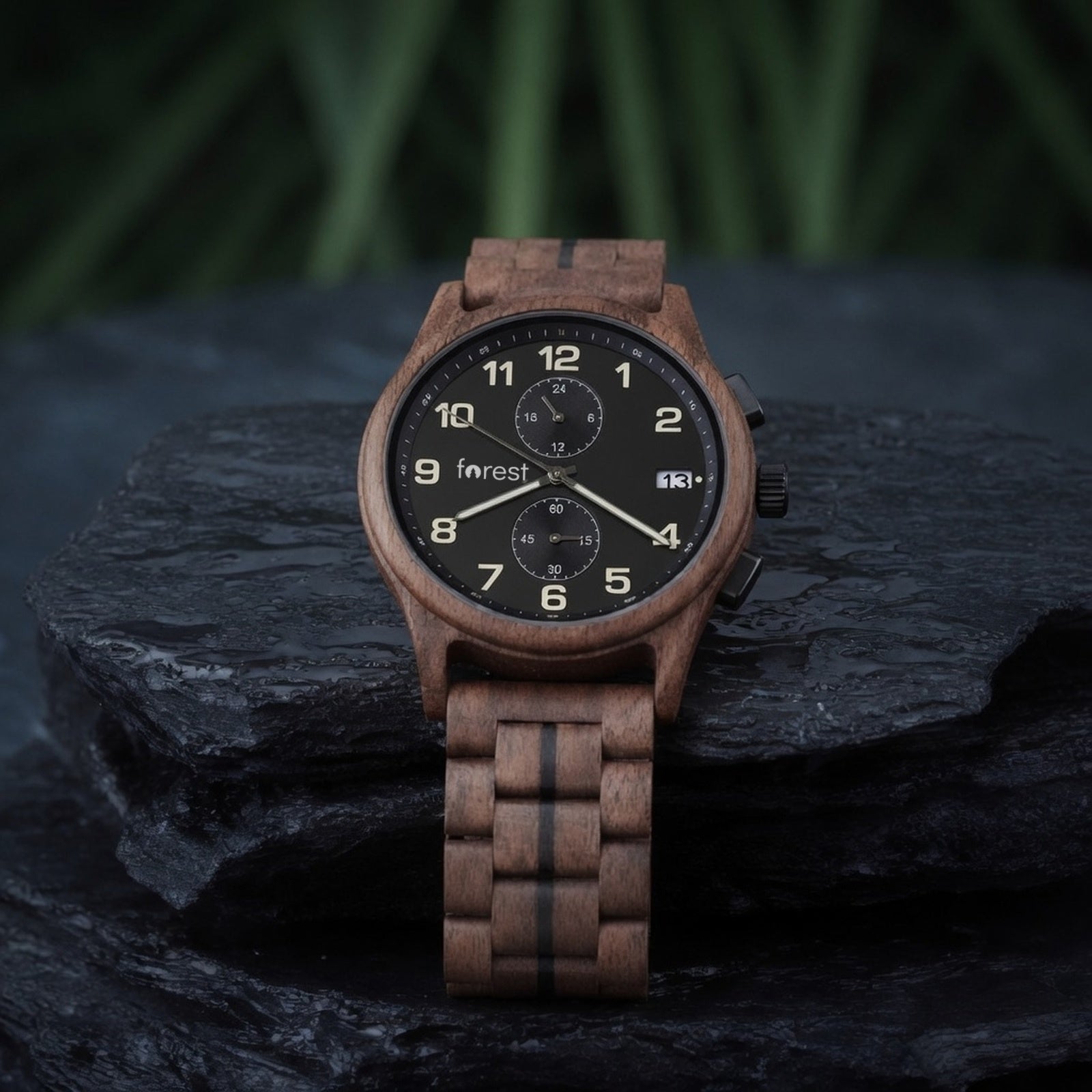 Raven walnut chronograph with black dial, draped over the edge of a slate slab, bracelet hanging
