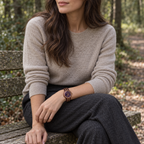 Royal watch worn with an oatmeal knit top, seated on a woodland bench