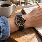 Scout wooden watch on a man's wrist at a cafe table beside a notebook and coffee