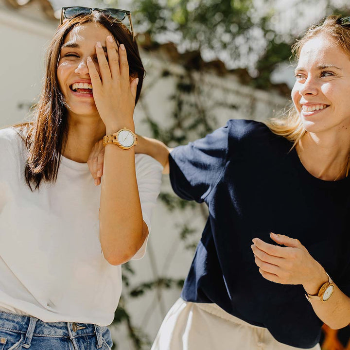 Two women laughing wearing wooden watches