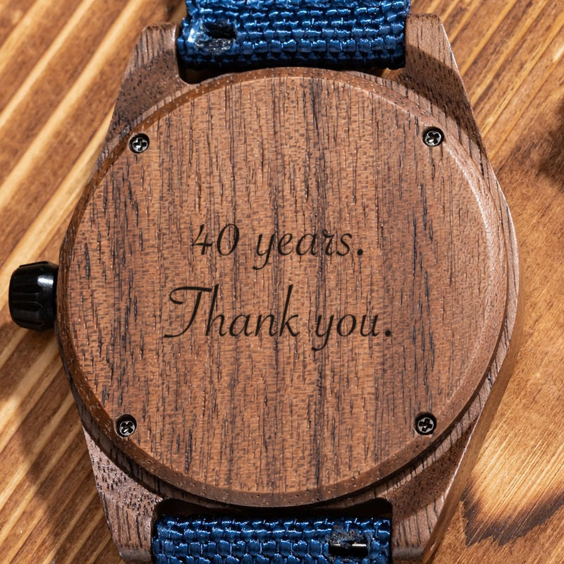 Fond en noyer de la montre Scout avec son bracelet bleu, gravé d’un message